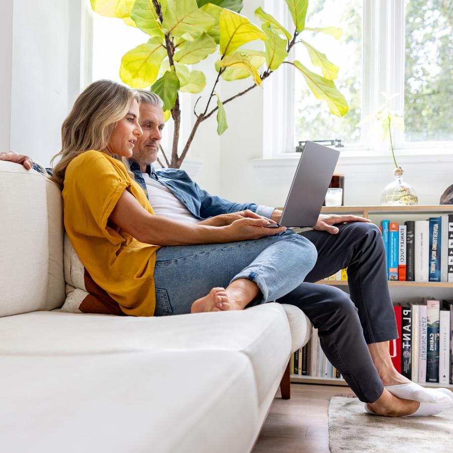 Couple on couch reading about fraud trends on a laptop